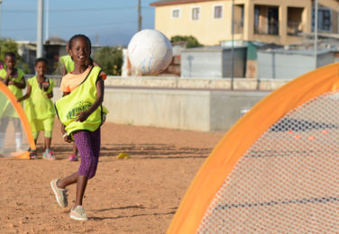 Girl in Africa shooting on a Pugg soccer gaol - Grassroots Soccer and Pugg partnership image